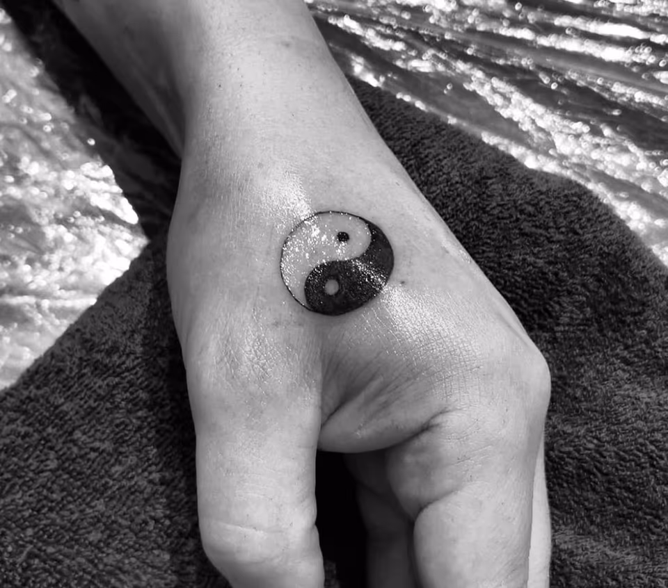 Yin-Yang-Symbol in Schwarz auf dem Handrücken
