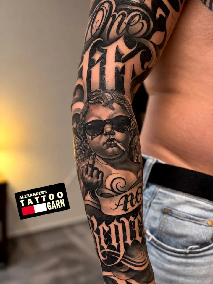 Chicano-Sleeve am Unterarm: Engel mit Sonnenbrille und Zigarette, dazu Script-Lettering in Black & Grey