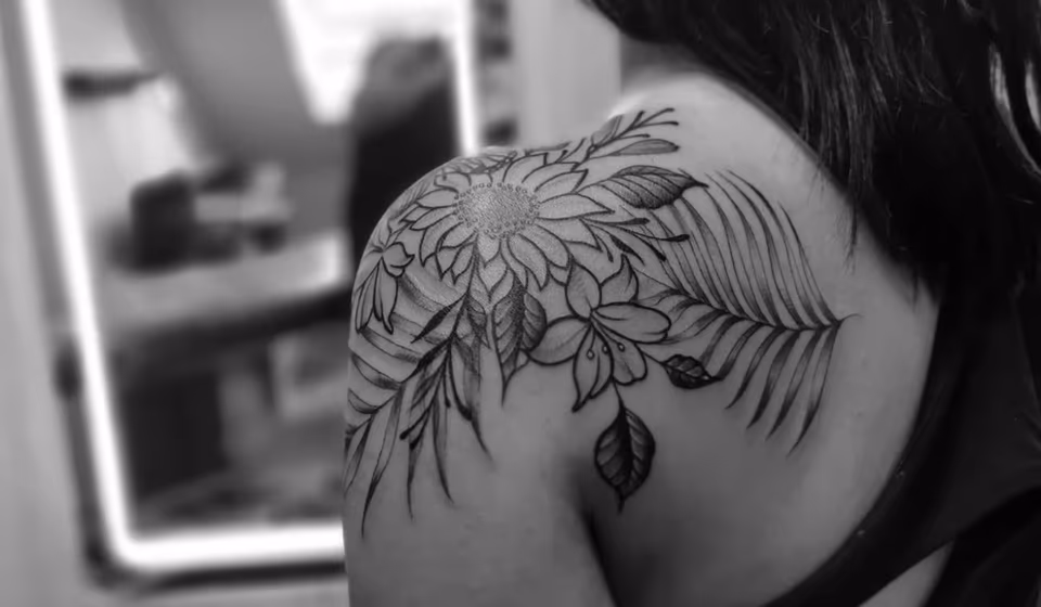 Sonnenblume und Farnwedel in feinen Linien über der Schulter