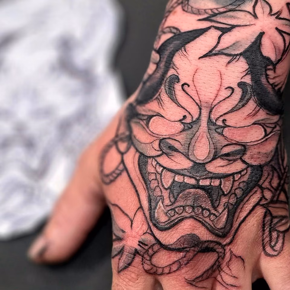 Hannya-Maske mit Ahornblättern und Seil in Black & Grey auf dem Handrücken