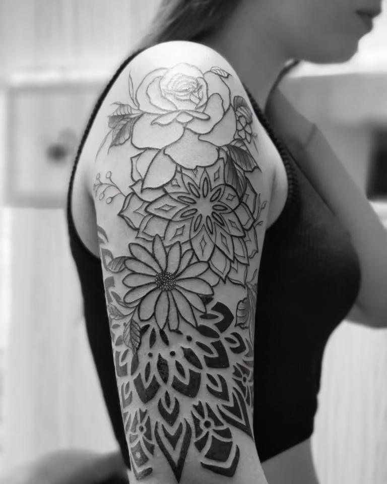 Rose und Blüten, die in ein schwarzes Mandala-Ornament übergehen, am Oberarm